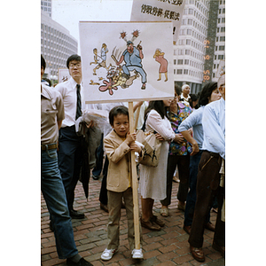 Chinese boy holding a protest sign among a crowd of protesters at a rally for Long Guang Huang in City Hall Plaza in Boston
