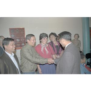 Member of the Consulate General of the People's Republic of China shakes hands with several attendees at a welcome party held for the Consulate General's visit to Boston