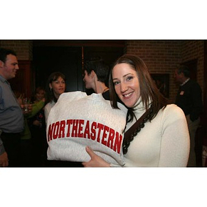 A woman holds up a Northeastern sweatshirt at the New York City town meeting