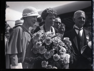 Amelia Earhart reception: Earhart with bouquet of flowers, standing betweem her mother and acting Mayor of Boston Edward M. Gallagher, in front of her Lockheed Vega 5b airplane