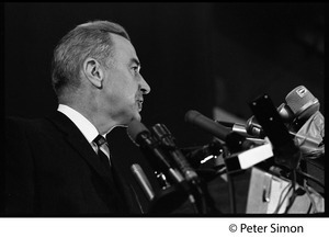Presidential candidate Eugene McCarthy behind a bank of microphones giving a speech at Boston University