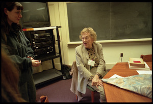 Julia Child, seated at a table, talking with students