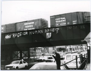 Graffiti on the train overpass on Main Street: 'Arms race or human race??'