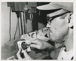 Man measuring his work at a drill press