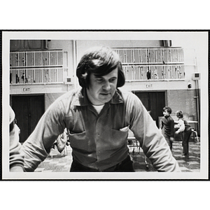 A male staff member spreads his arms out and looks down in an auditorium