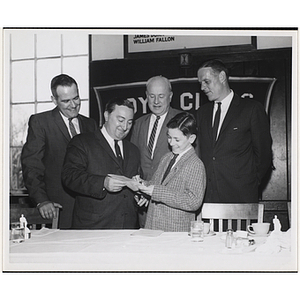 A boy signing a paper for State Senator John E. Powers while three others look on from behind at the "Annual Church Day Breakfast at the South Boston Clubhouse, April 10, 1960"