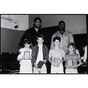 Two former Boston Celtics players, Sly Williams, left, and Sam Vincent, pose for a group picture with a girl and three boys displaying their awards at a Kiwanis Club's awards ceremony