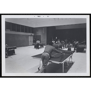 Two boys play table tennis in a hall