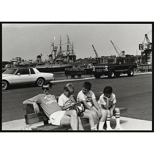 Three boys sitting on a bench next to their counselor at the Charlestown Navy Yard