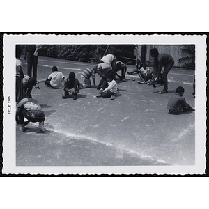 Boys put on and tie their shoes on a blacktop during a game on Tom Sawyer Day