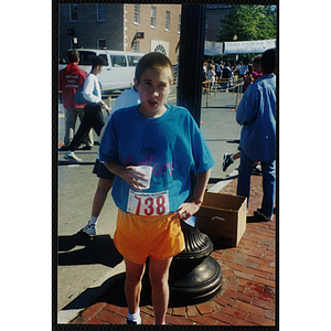 A teenage boy holds a cup of water at the Battle of Bunker Hill Road Race