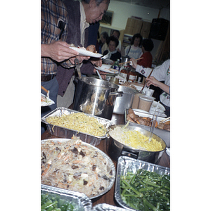 Members of the Chinese Progressive Association serve food from a buffet ...