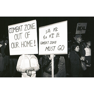 Chinatown residents protest against the Combat Zone, the red-light district in Boston, holding three signs that read, "Combat Zone Out of Our Home!"; "Combat Zone Must Go"; and, "Pimps, Get a Real Job"