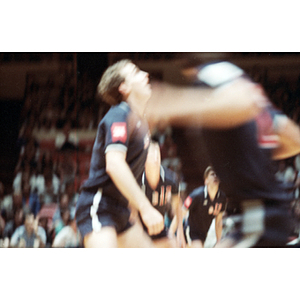 United States Men's Volleyball Team member looks upward and anticipates the ball, while a teammate runs in the foreground