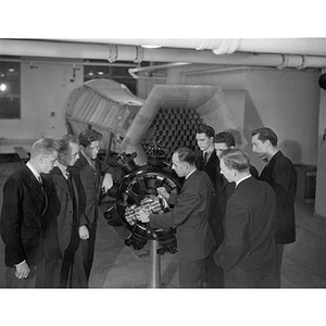 An engineering professor lecturing students while standing next to a large motor