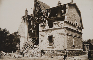 View of damaged building with civilians standing nearby
