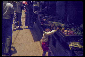 Street scene, with child next to fruit stand