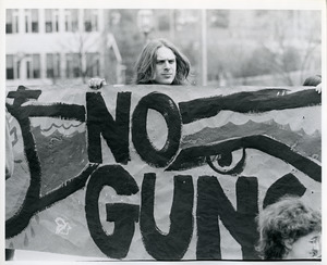 Board of Trustees fee increase demonstration: protestor holding banner that reads, 'no guns'