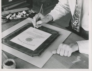 A man making a painted proof of the 1951 president's trophy plaque