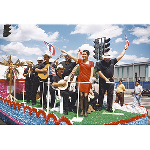 People on a float waving flags or playing musical instruments at the Festival Puertorriqueño