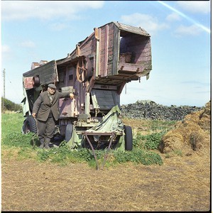 Robert Kennedy from Ardglass, Co. Down, standing beside a traditional, very old, pink threshing machine