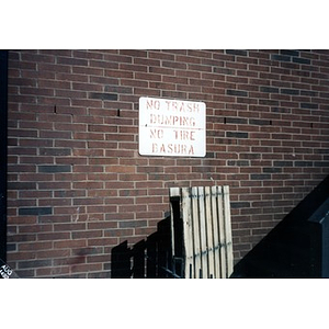 "No trash dumping" sign affixed to the brick wall of a building.
