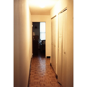 A narrow hallway with parquet floor in a Villa Victoria apartment.