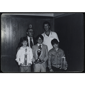 Two men standing with three boys holding their trophies during a Boys' Clubs of Boston Awards Night