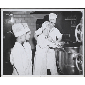 A member of the Tom Pappas Chefs' Club stirs soup ingredients as a cook and two other members look on in a Brandeis University kitchen