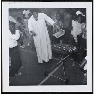 A man fans a grill of shesh kababs at a picnic