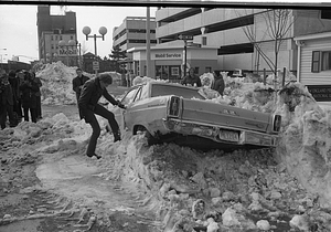 Unidentified man opening door of car buried in snow on Cambridge Street