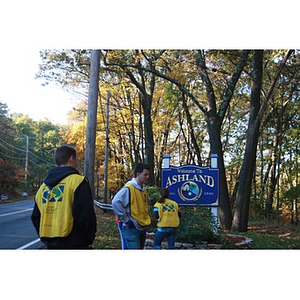 Volunteers stand in front of Welcome to Ashland sign