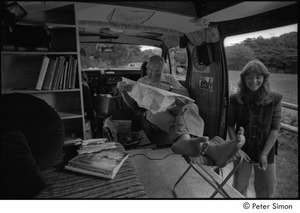 Ram Dass in his van: Ram Dass studying a map, with Ronni Simon standing outside the doorway