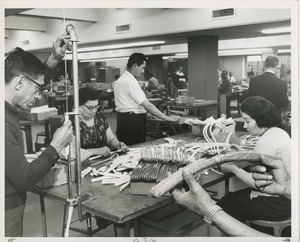 Men and women constructing clothes hangers