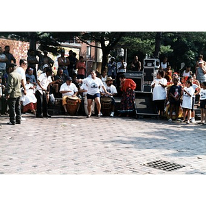Girl performing a dance in the plaza accompanied by drummers at Festival Betances.