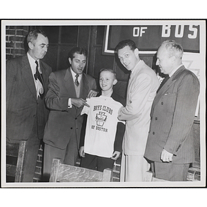 Unidentified men presenting a boy with a Boys' Clubs of Boston t-shirt at an awards event held by the Boys' Clubs of Boston and the Knights of Columbus Bunker Hill Council