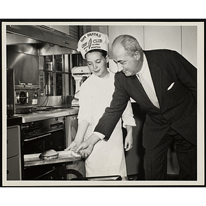 A member of the Tom Pappas Chefs' Club poses at an open oven with an unidentified man