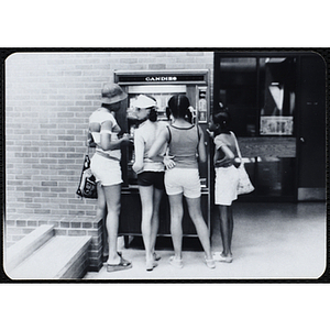 A group of girls stand at a candy vending machine