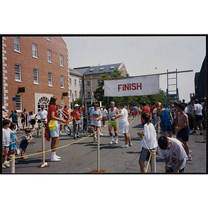 Runners reach the finish line as spectators look on during the Bunker Hill Road Race