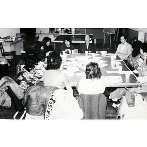 Members of the Chinese Progressive Association sit around a table during a meeting at their office