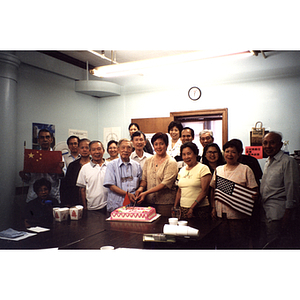 Chinese Progressive Association members gather around a man and women who are cutting a cake