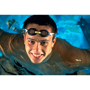 Male swimmer posing in the water with his goggles on his forehead