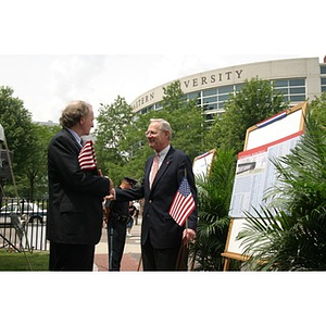 Two men converse near the plans for the Veterans Memorial at the groundbreaking ceremony