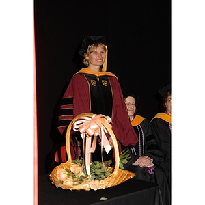 Carol Glod, a professor at the School of Nursing, stands near a basket of roses at the School of Nursing convocation ceremony