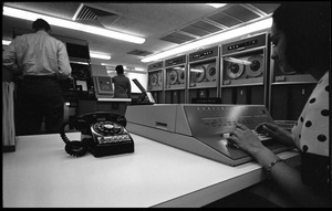 Computer room scene: woman at the console of a Honeywell Model 400 mainframe, with printer and card reader (?) in background