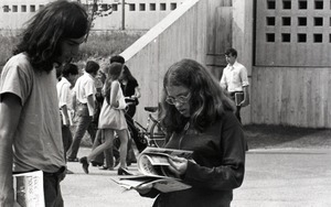 Bill Grabin showing Free Spirit Press magazine to young woman in front of the UMass Amherst Campus Center Parking Garage