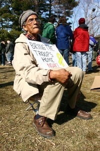 Elderly man seated with a sign reading 'Bring the troops home now!': rally and march against the Iraq War