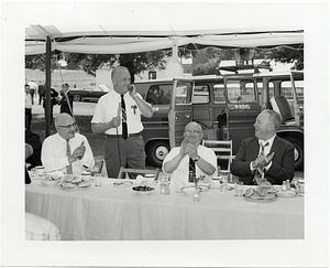 Mayor John F. Collins applauds a speaker at an outdoor luncheon