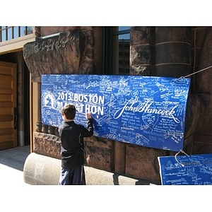 Boy signing marathon poster at Boylston Street firehouse