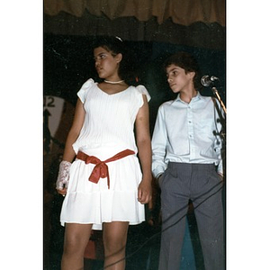 Boy and girl in dress clothes at a microphone, looking off to one side.
